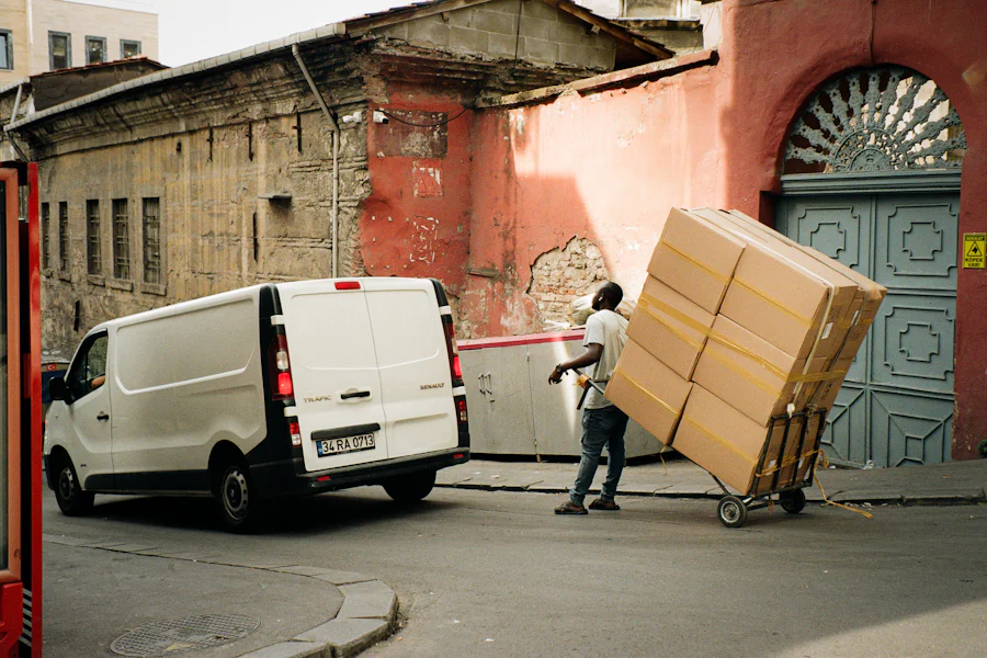 Umzugshelfer transportiert Kartons mit der Sackkarre zum Transporter