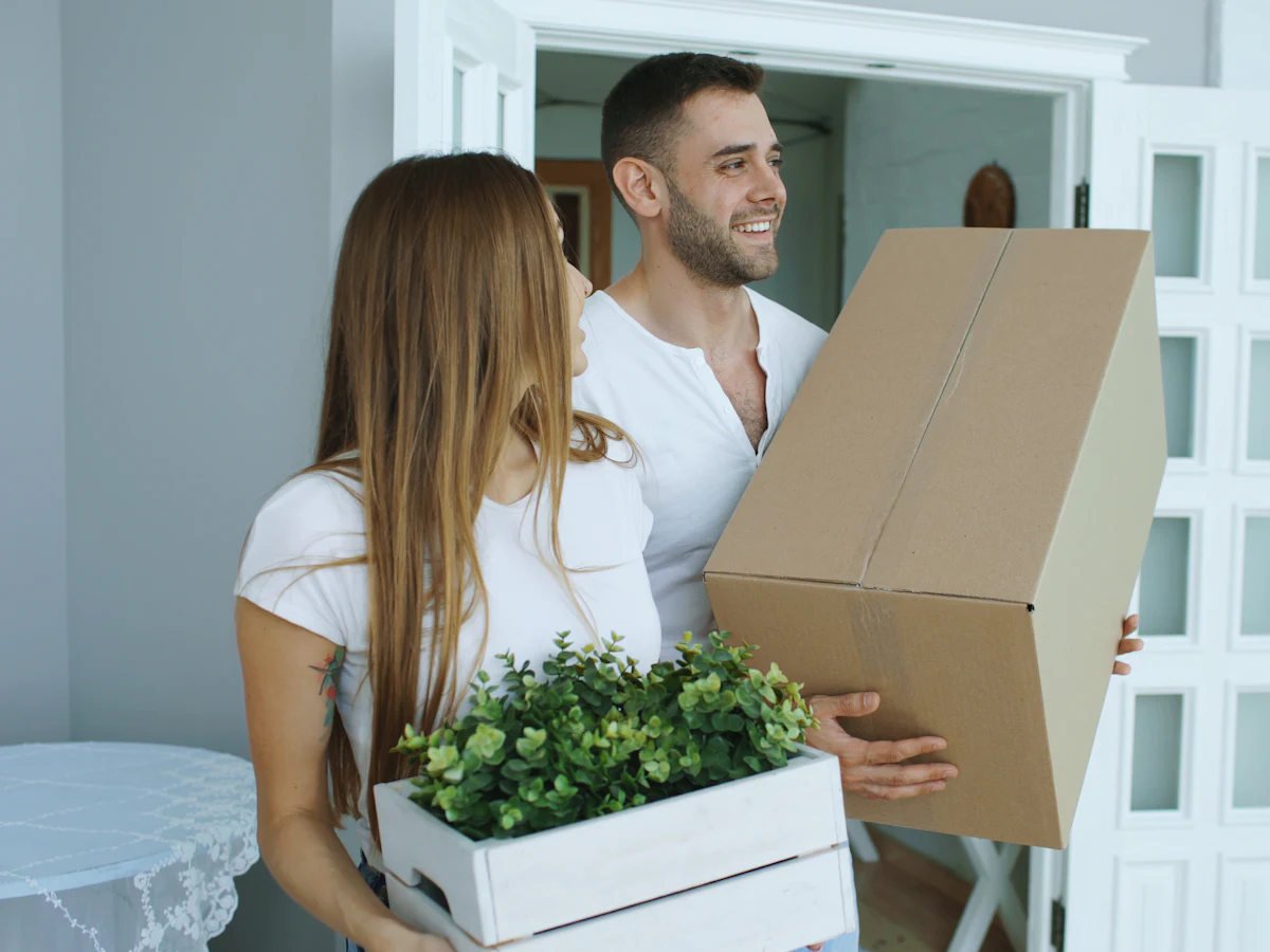Zufriedenes Paar nach dem Umzug mit Kartons in der neuen Wohnung